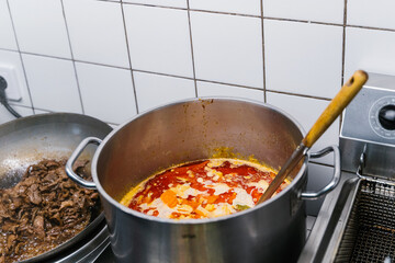 Large pot of Thai red curry simmering in a professional kitchen. Traditional Asian dish with coconut milk, spices, and vibrant red sauce.