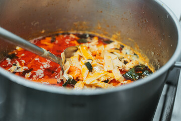 Large pot of Thai red curry simmering in a professional kitchen. Traditional Asian dish with coconut milk, spices, and vibrant red sauce.