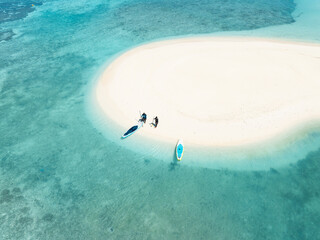 Aerial view of sun-kissed sands meet the turquoise embrace of the ocean, where paddleboards rest, inviting adventure and serenity, Naavaidhoo, Haa Dhaalu, Maldives.