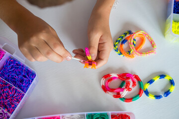 Colorful Loom Bracelets Being Crafted by Hand on White Background