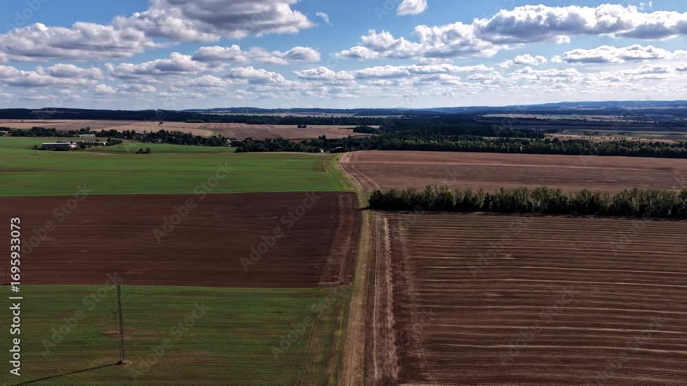 Poster hyperlapse of floating and dissolving clouds over a landscape of fields and meadows from a drone