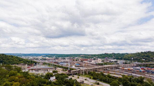 Cincinnati, United States - 22 August 2025: Aerial view of the intricate web of railway tracks and the industrial heart of the city nestled amongst verdant hills.