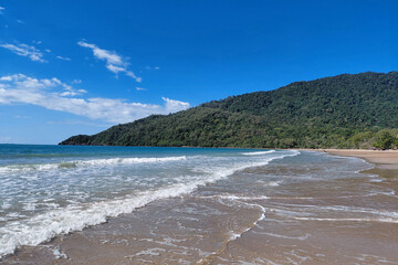 Serene tropical beach with lush green hills and clear blue sky