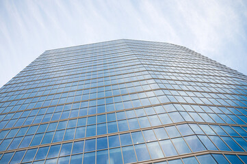 Modern glass skyscraper against blue sky with reflective windows