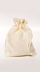 Beige burlap gift bag with drawstring tied on neutral background