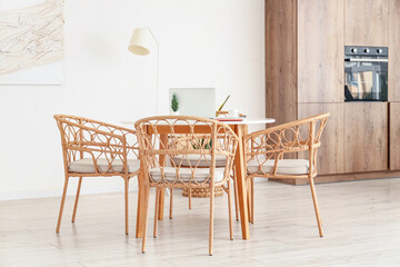 Table and wicker chairs near white wall in dining room
