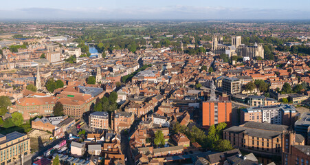 Obraz premium Aerial image of York with York Minster, historic rooftops, and modern buildings in contrast at sunrise.