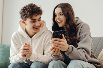 Teenagers sharing social media content on smartphone sitting on sofa