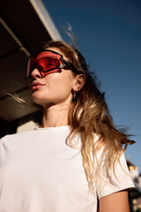 Fashionable woman wearing red sunglasses under bright sunlight