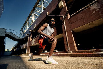 Athlete performing warm-up stretch under sunny urban surroundings
