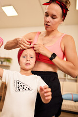 Mother ties headscarf for young daughter in a cozy home setting