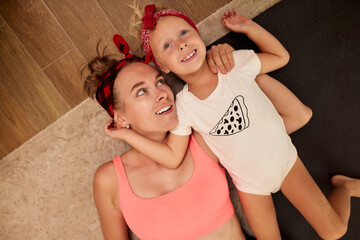 Mother and daughter bonding indoors while relaxing on a carpeted floor