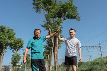 Two close friends joyously share a cheerful highfive outdoors, surrounded by natures beauty