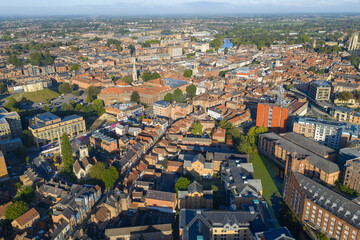 Obraz premium Aerial image of York showing Clifford’s Tower, historic rooftops, and modern buildings in morning sunlight.