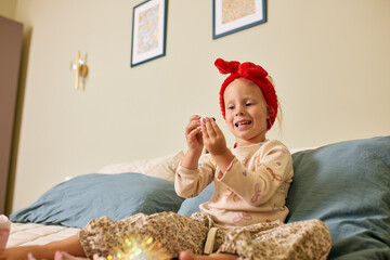 Joyful child playing with toys on a bed in a cozy bedroom