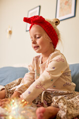 Young girl wearing a red headband and playing indoors with colorful decorations