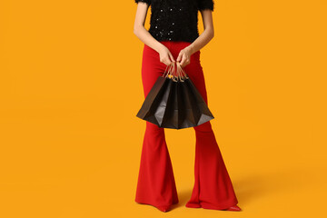 Young woman with shopping bags on yellow background. Black Friday Sale