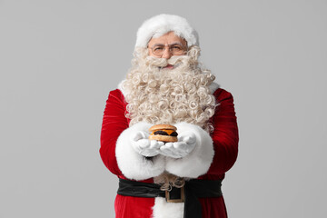 Santa Claus with tasty burger on grey background