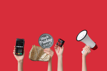 Female hands with payment terminal, megaphone and gift box on red background. Black Friday Sale