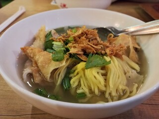 Bakso Pangsit, an Indonesian food contains noodle and meatball in the broth soup. with celery and fried shallot on top. 
