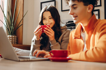 Students drinking coffee and working on laptop in cafe