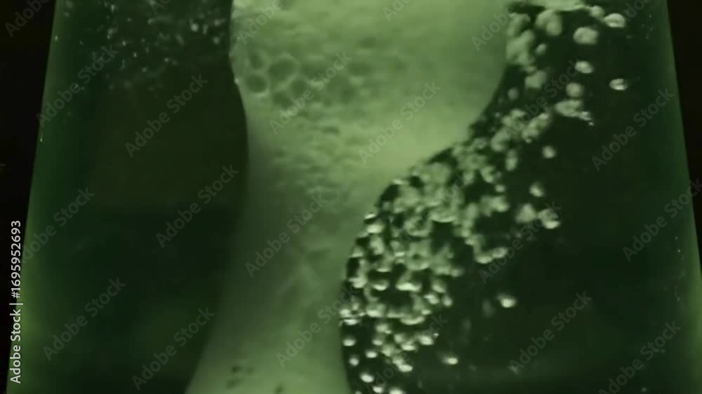 Poster close-up of a green lava lamp with bubbling liquid, showing movement and texture.
