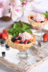 French pancakes with whipped cream filling with strawberries and blueberries, strawberry syrup, almond petals. Served in a glass and garnished with mint.  