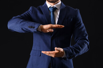 Businessman showing something on dark background, closeup. Goal concept