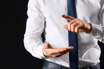 Businessman showing something on dark background, closeup. Goal concept