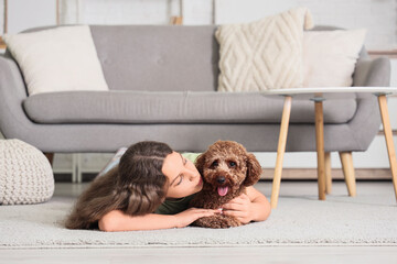 Teenage girl with Poodle dog lying on carpet at home