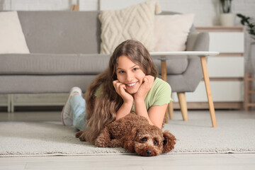 Teenage girl with Poodle dog lying on carpet at home