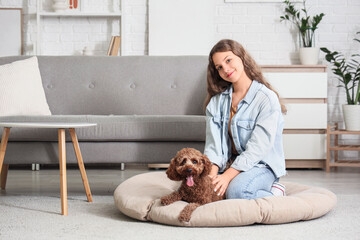 Teenage girl with Poodle dog on pouf at home
