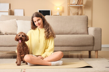 Sporty teenage girl with Poodle dog sitting at home