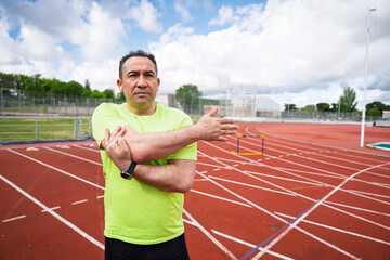 Senior athlete stretching arms on running track