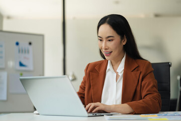 Businesswomen hand working with tablet and laptop computer with documents on office desk in modern office.
