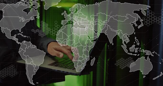 Typing mature Korean male's hands on laptop at desk, showing world map, green hexagonal patterns - Powered by Adobe