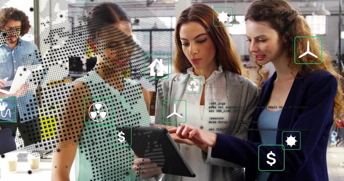 Team examining tablet in office featuring green icons, money icons, code icons, laptop, coffee cups