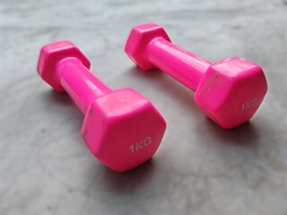 A pair of 1kg pink dumbbell on floor. Training and health care start with simple steps.