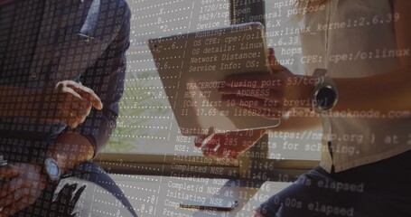 Scanning network on tablet by two IT consultants wearing casual shirts by blinds