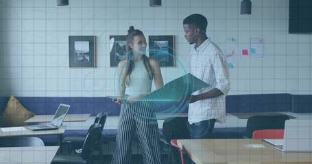 Two designers reviewing data visualization in coworking space, with blueprint and tablet