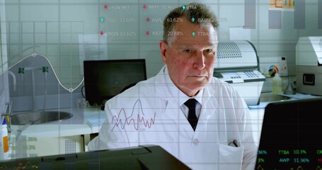 Senior scientist wearing lab coat and tie analyzing real-time data on monitors in lab, with sink