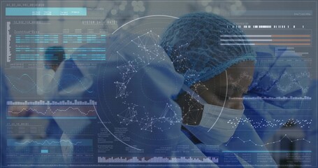 Standing surgeon in blue scrubs and masks operating in suite, with digital charts, brain overlays