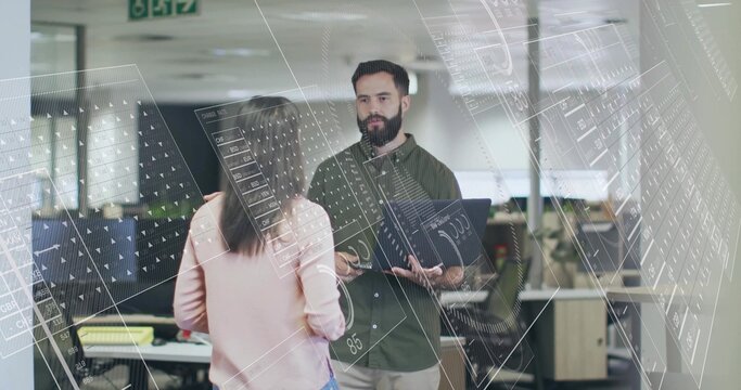 Discussing office professionals examining schematic overlays in open-plan office, with laptop