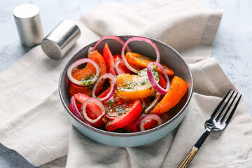 Bowl of fresh tomato salad with red onion on grey background, closeup