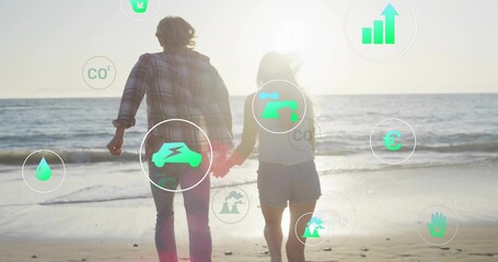 Walking couple holding hands toward ocean at sandy shore, with floating eco and financial icons