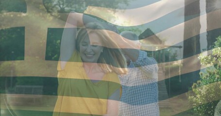 Dancing senior man and adult woman twirling on paved garden path, with benches and stone steps