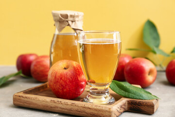 Bottle and glass of fresh apple cider with fruits on grey table