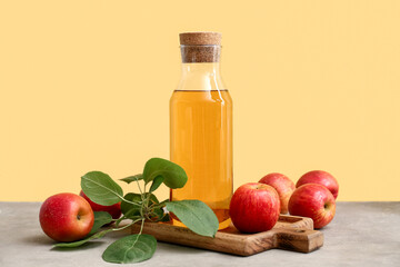 Bottle of fresh apple cider and fruits on grey table