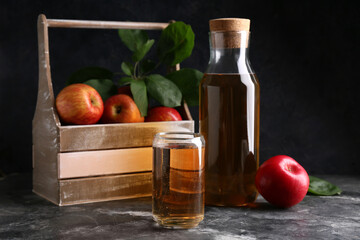 Glass and bottle of fresh apple cider on dark background