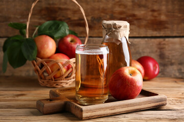 Bottle and glass of fresh apple cider with fruits on wooden background